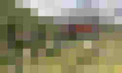 Moderne Standseilbahn fährt durch grüne Alpenlandschaft mit Bergen im Hintergrund